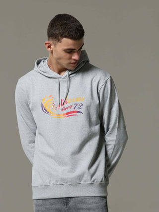 Person wearing a gray hoodie with colorful text and graphics on a plain background