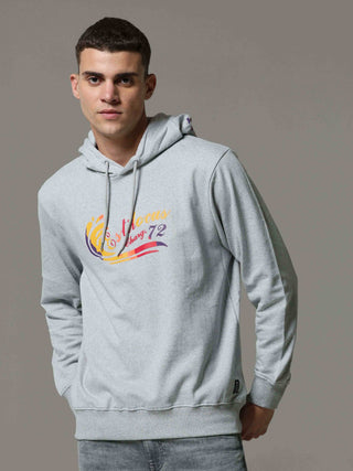 Man wearing a gray hoodie with colorful graphics on a plain background