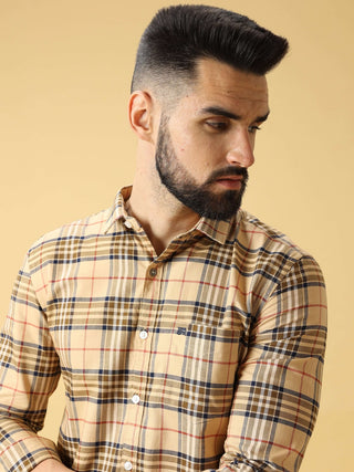Man wearing a plaid shirt against a beige background.