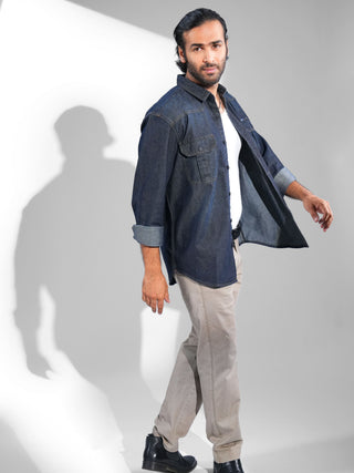 Man wearing a denim shirt and beige pants on a white background.