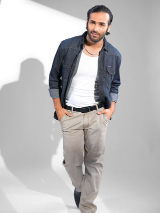 Man wearing a blue shirt over a white t-shirt and beige pants on a white  background