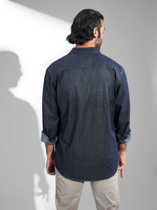 Man wearing a dark denim shirt against a white background.