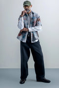 A man wearing an oversized plaid shirt and pants, showcasing a casual and relaxed style.