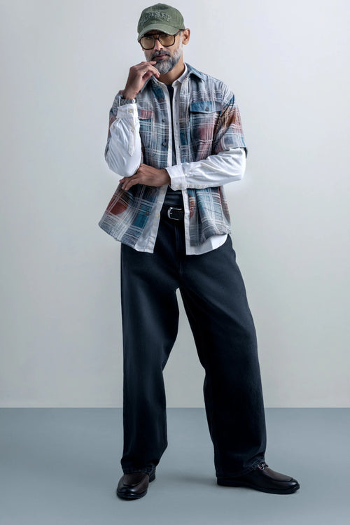A man wearing an oversized plaid shirt and pants, showcasing a casual and relaxed style.