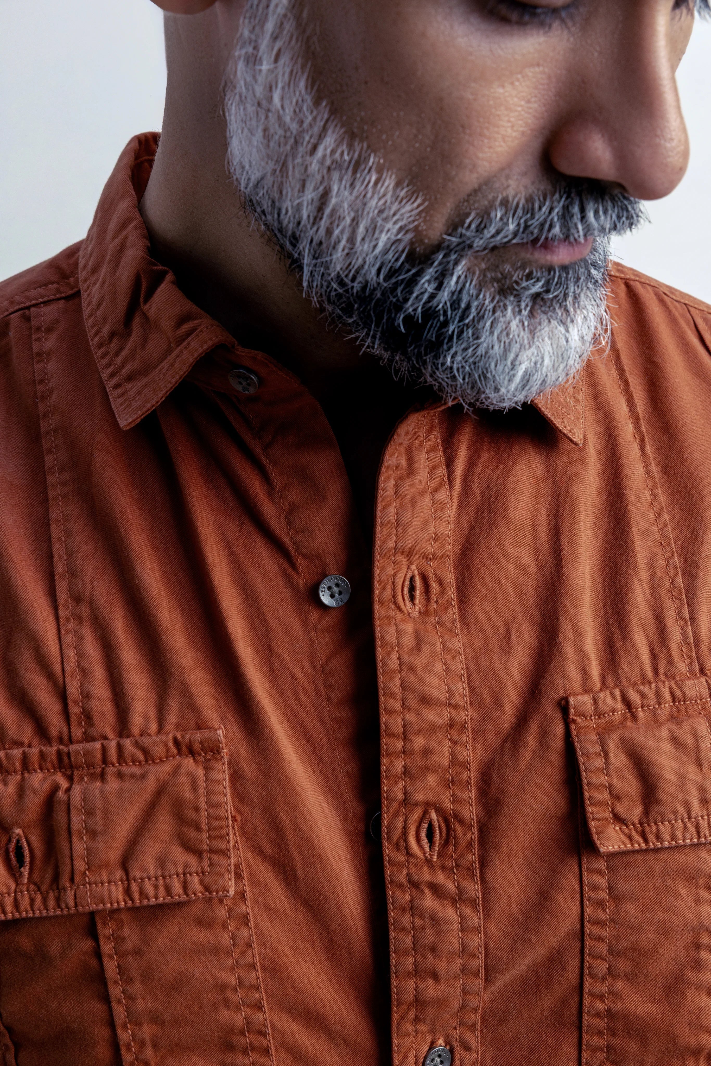 Close-up of a man wearing an shirt with a neutral background.