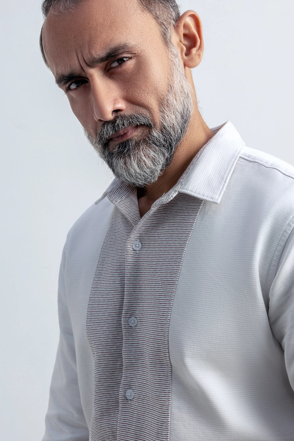 Man wearing a white shirt with a white collar against a white background.
