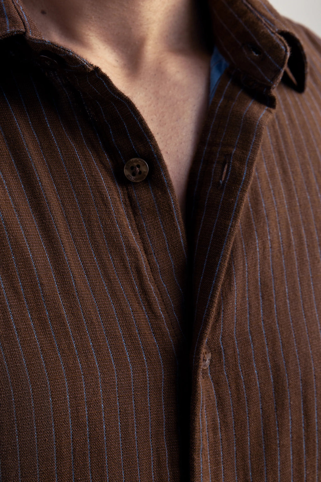 Close-up of a brown pinstripe shirt with a collar and buttons.