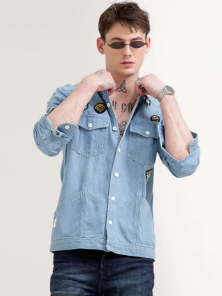 Man wearing a light blue denim jacket on a plain background.