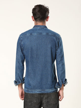 Person wearing a blue denim jacket and showing backside of the jacket on a white background.