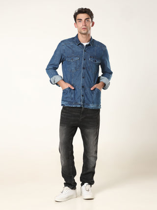 Man wearing a blue denim jacket and black jeans on a white background.