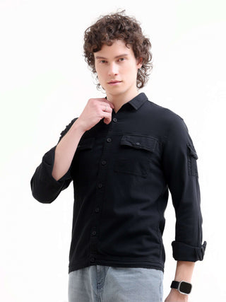 Man wearing a black long-sleeve denim shirt on a white background.