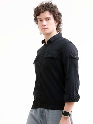 Man wearing a black denim shirt on a white background.