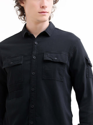 Black button-up denim shirt worn by a person on a white background.