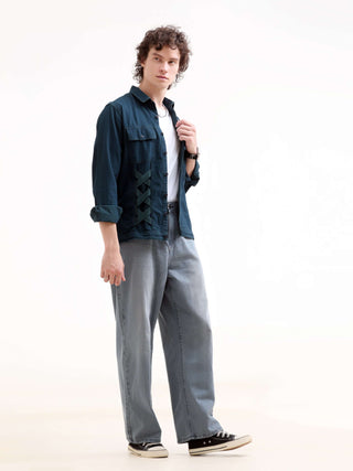 Man wearing a dark blue denim shirt, and gray pants on a white background.