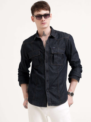 Man wearing a black denim shirt and sunglasses on a white background.
