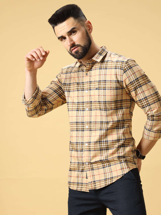 Man wearing a beige checkered shirt posing against a light studio background.